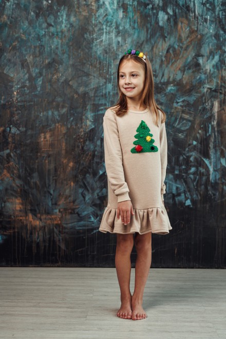 Girl's sand dress with a ruffle and a decorated Christmas tree